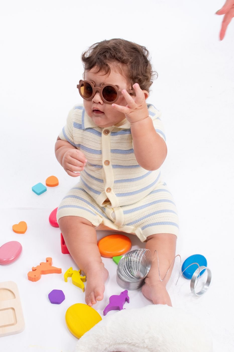 Toddler playfully exploring with sunglasses and sensory toys