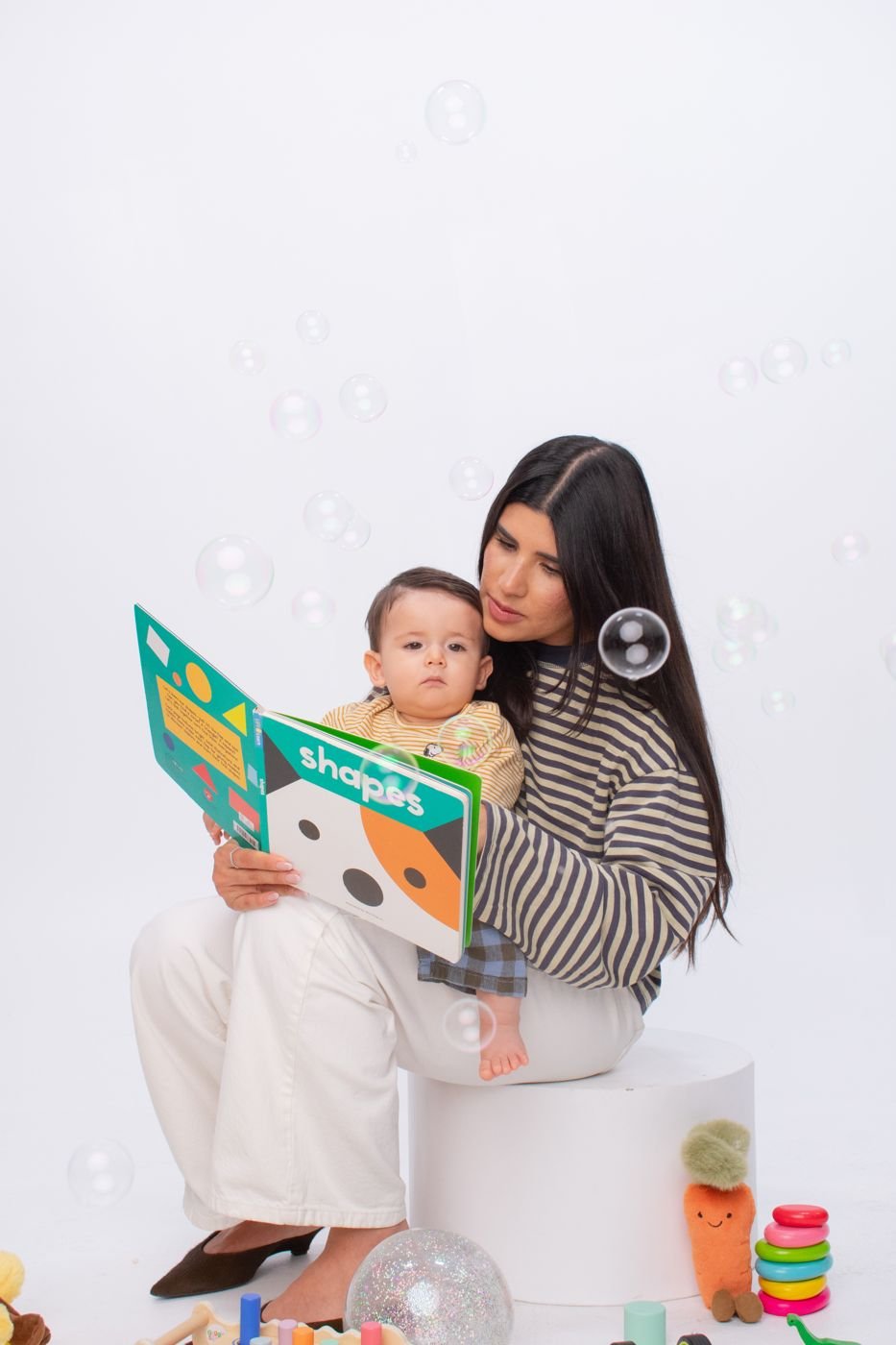Parent and toddler reading a book together, engaged and smiling